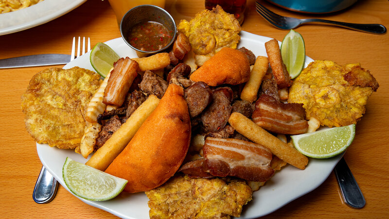 A variety of beef, pork, chicken, pork rinds, Colombian chorizo, cassava potatoes, french fries, tostones, and limes